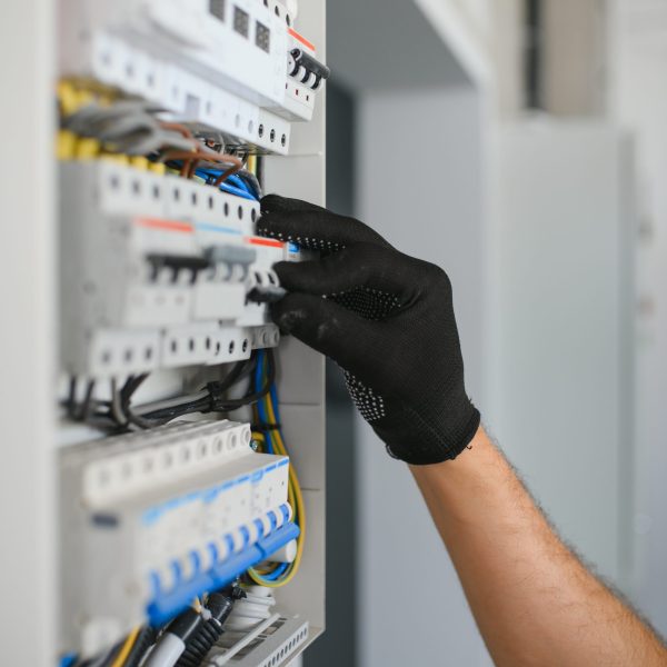 A male electrician works in a switchboard.